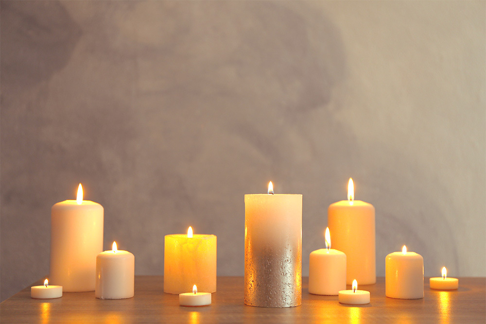 Ansammlung von brennennden Kerzen vor warmen Hintergrund