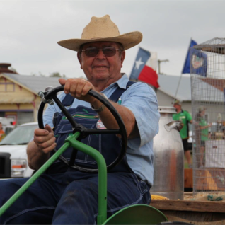 Mr. Harvey Schumacher on his restored John Deere pulling a float of young turkeys through the Turkeyfest Parade as part of the 100th Anniversary Cuero Turkey Trot.