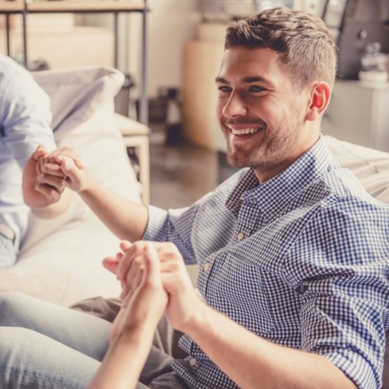 young man smiling holding support system hands