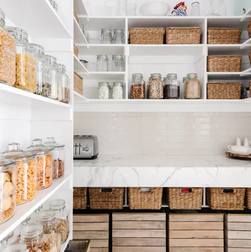 organized pantry with decanted jars and rattan baskets